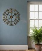 Decorative wall clock on a blue wall with a window and plant in the background