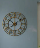 Decorative wall clock with Roman numeral design on a blue wall.