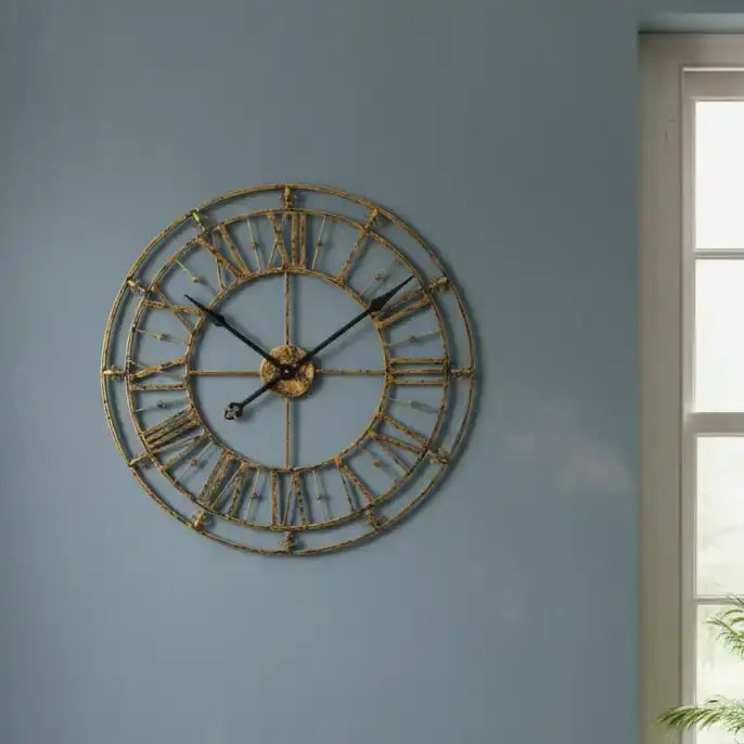 Decorative wall clock with Roman numeral design on a blue wall.