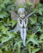 Statue of a fairy sitting among green leaves