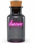 A small dark glass bottle with a cork stopper, featuring a glowing pink neon-style 'dream' sign on the front, shown against a plain white background.