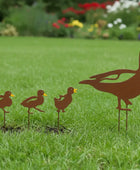 Metal duck family sculpture on grass with flowers in the background