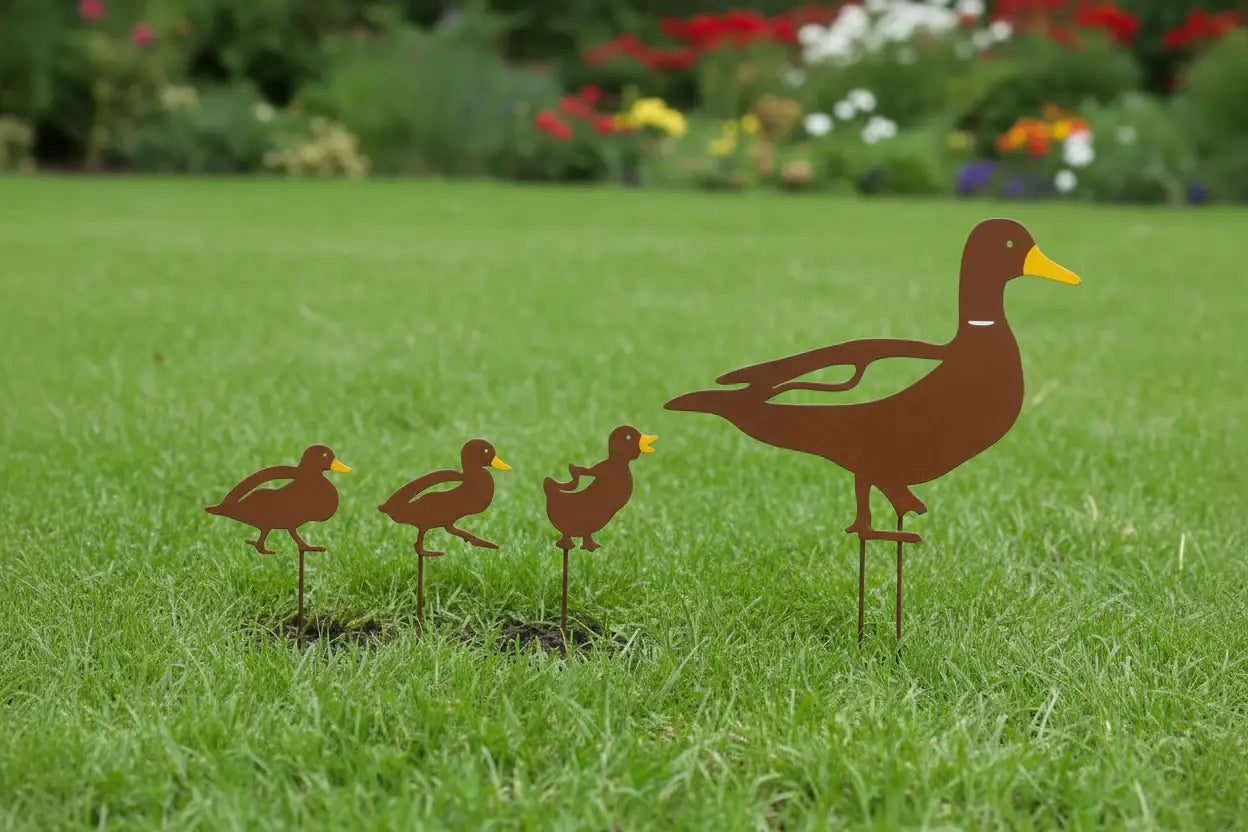 Metal duck family sculpture on grass with flowers in the background