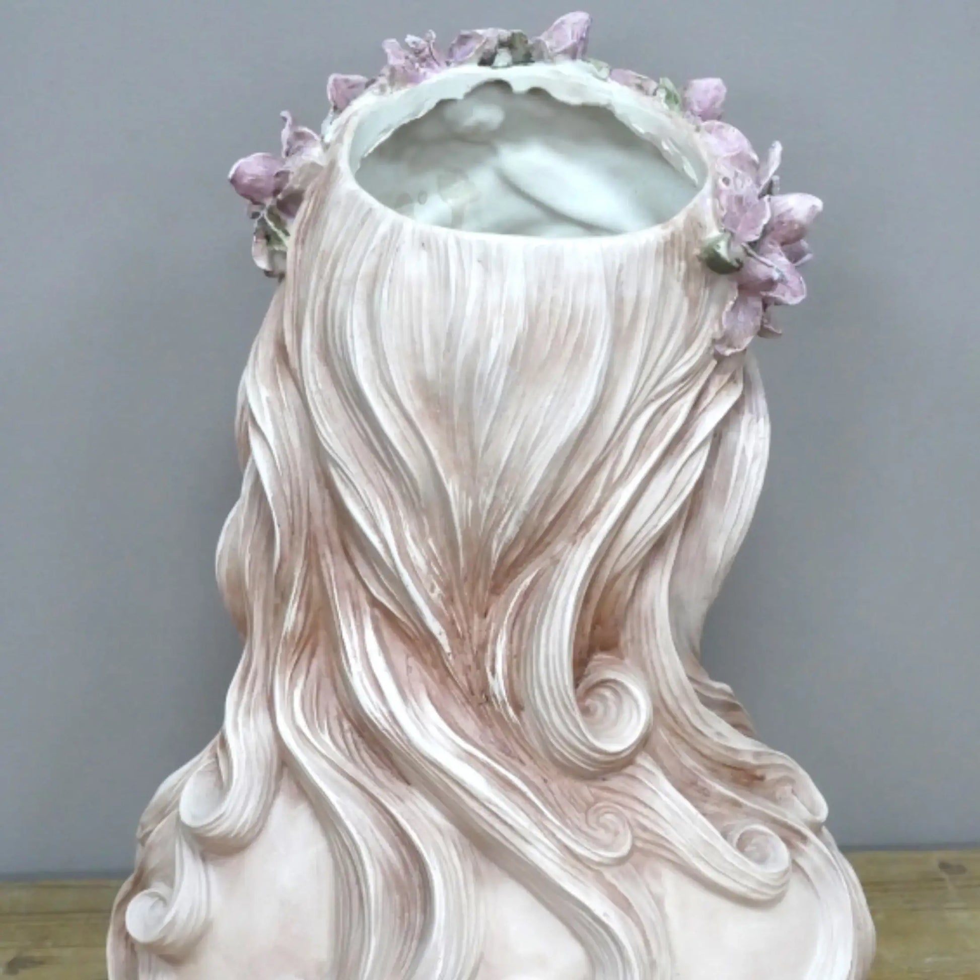 Vase shaped like a woman with long hair and flowers, on a neutral background