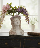 Decorative vase shaped like a woman's head with floral arrangement on a wooden surface.