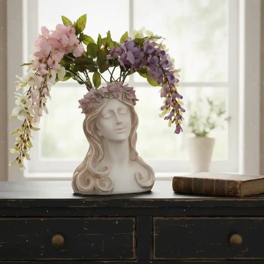 Decorative vase shaped like a woman's head with floral arrangement on a wooden surface.