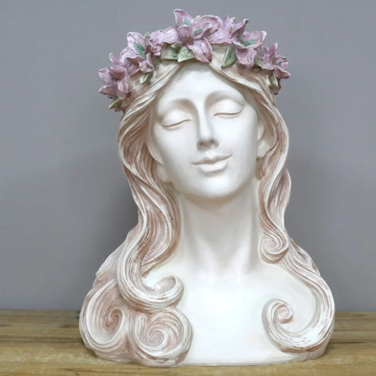 Decorative bust of a woman with a floral crown on a wooden surface and gray background