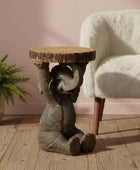 Wooden side table shaped like an elephant with a plant and chair in the background