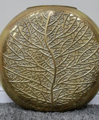 Decorative round object with leaf pattern on a plain background