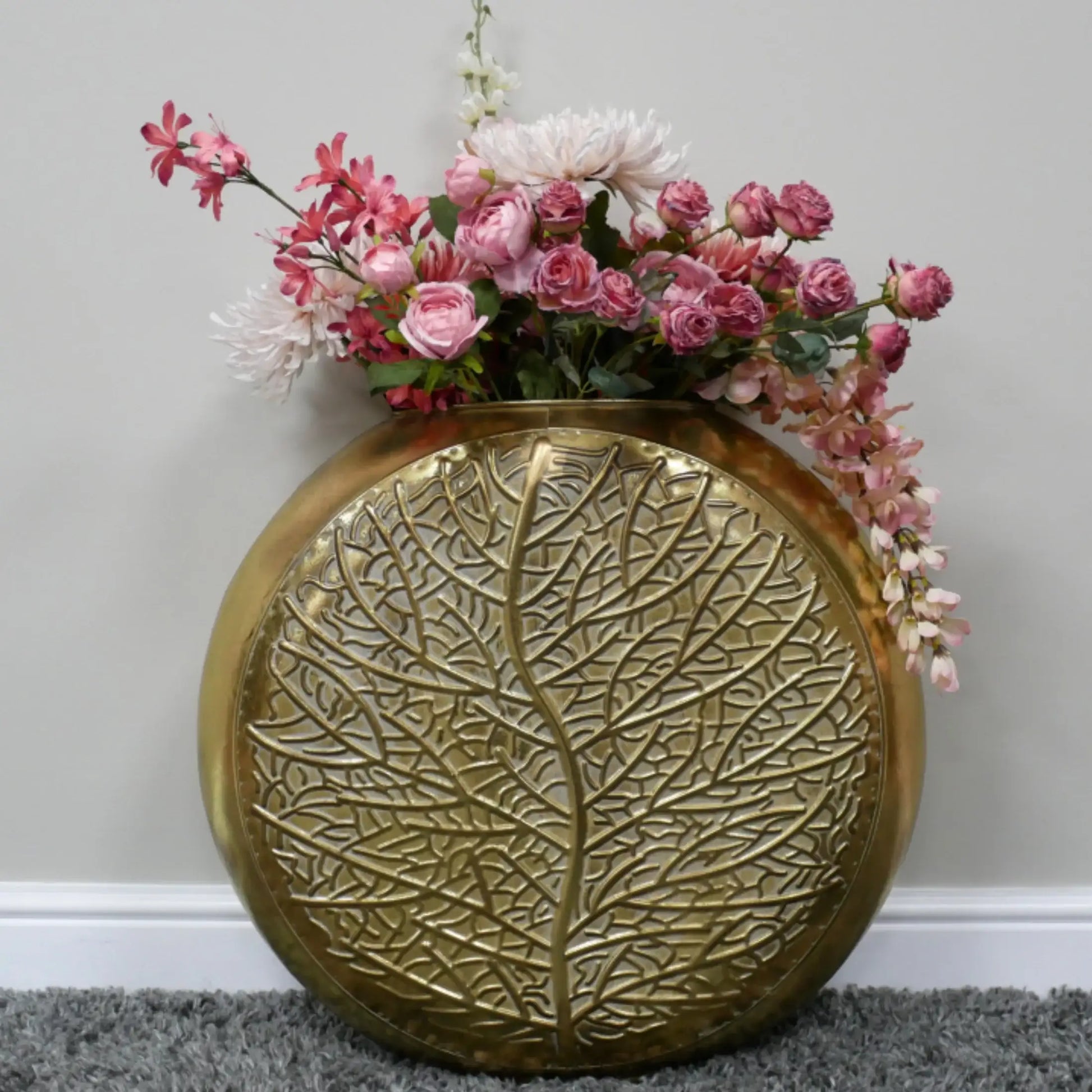 Decorative gold vase with floral arrangement on a gray surface