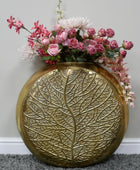 Decorative gold vase with floral arrangement on a gray surface