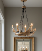 A rustic chandelier made from natural antlers with five candle-style bulbs, hanging in a hallway with a gold-framed mirror below.