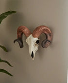 Decorative ram skull mounted on a wall with a plant and curtain in the background