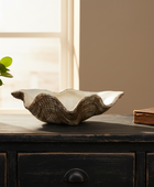 Decorative bowl on a wooden surface with a plant and book in the background