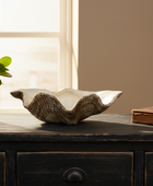 Decorative shell on a wooden surface with a plant and book in the background
