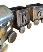 Three rustic metal train car planters with letters on a wooden floor.