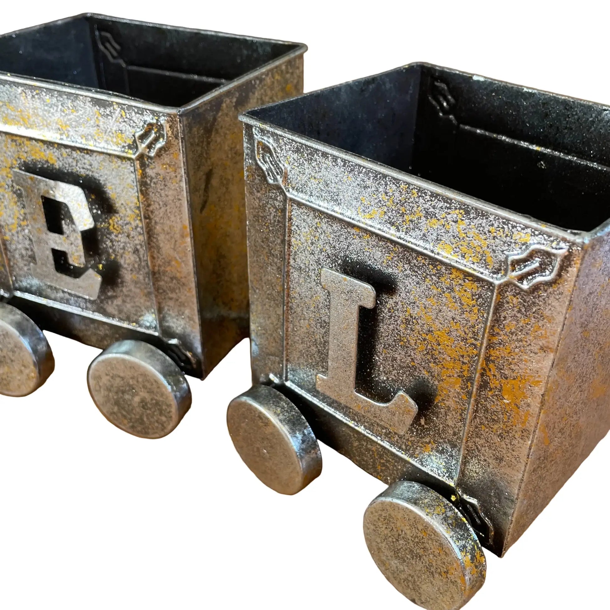 Two metal train car models with 'E' and 'L' on a wooden surface