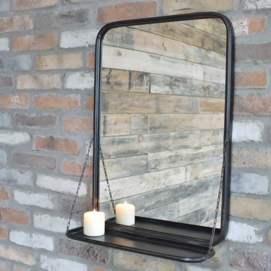Decorative mirror with a shelf hanging against a brick wall.