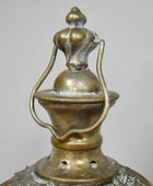 Close-up of a decorative metal lantern with intricate designs on a plain background