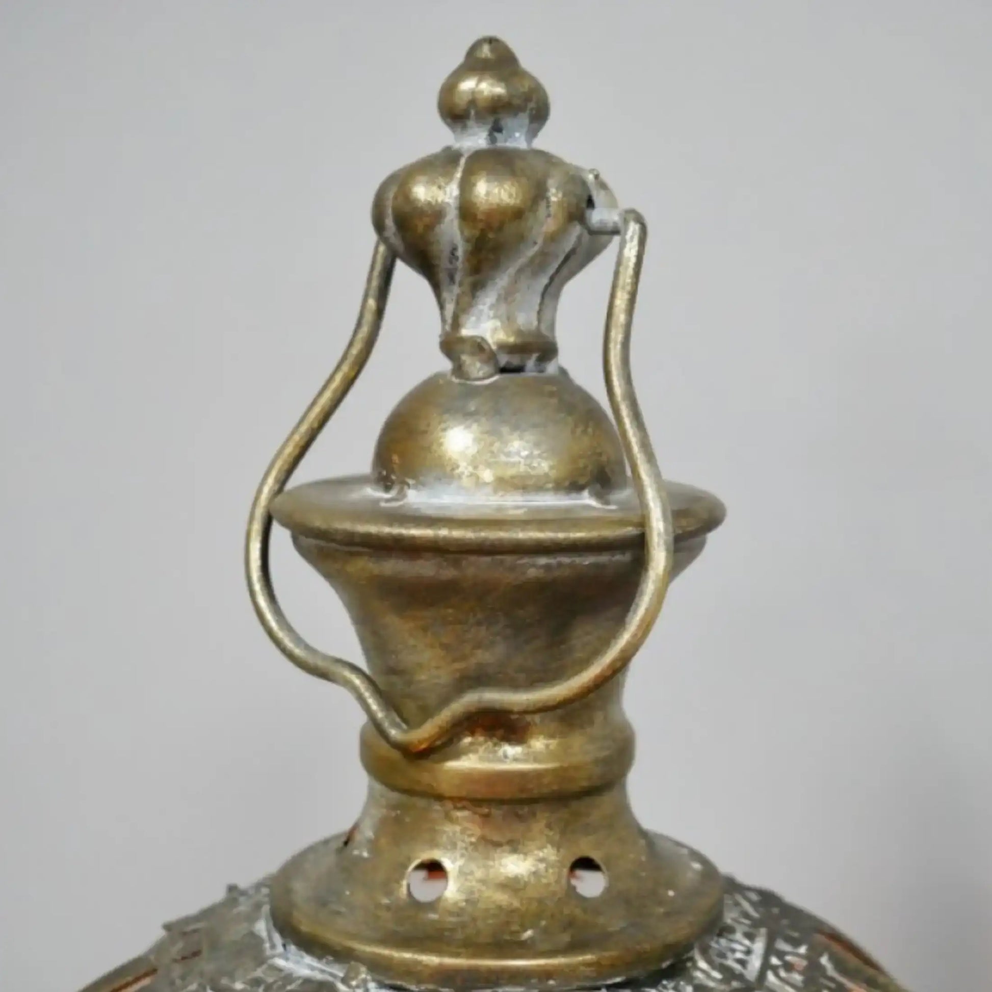 Close-up of a decorative metal lantern with intricate designs on a plain background