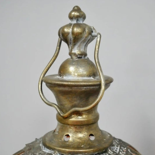Close-up of a decorative metal lantern with intricate designs on a plain background