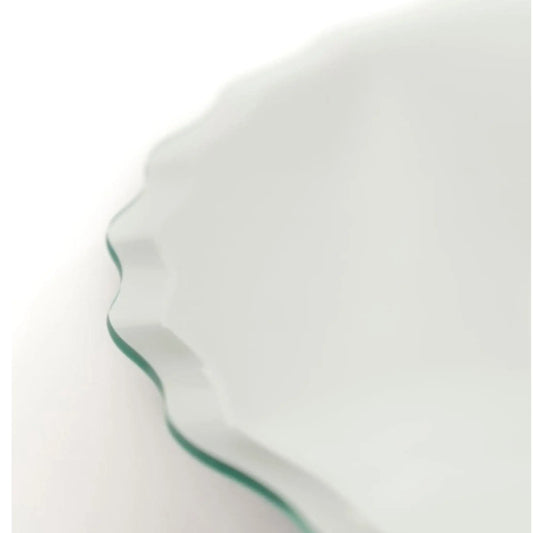 Close-up of a white ceramic plate with a green rim on a white background