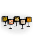 Set of five decorative candle holders with vintage-style labels on a white background