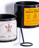 Two black candle holders with vintage-style labels on a white background