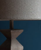 Close-up of a textured lampshade on a wooden base against a dark background