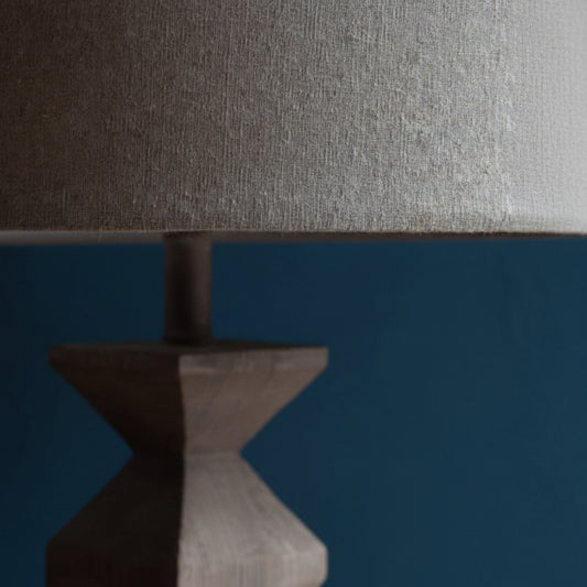 Close-up of a textured lampshade on a wooden base against a dark background
