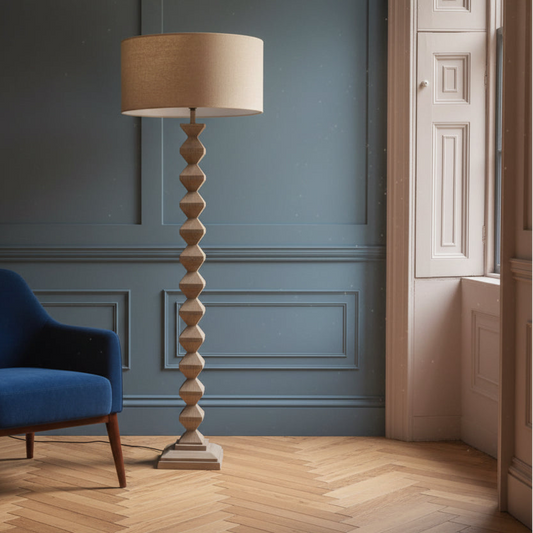 Tall floor lamp with a beige lampshade in a room with blue walls and wooden flooring.