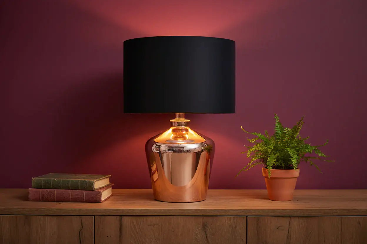 Table lamp with black shade and copper base on a wooden surface against a purple wall