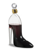 Clear glass bottle shaped like a high-heeled shoe filled with red liquid on a white background