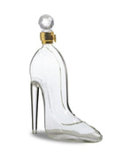 Clear glass shoe-shaped bottle with a gold cap on a white background
