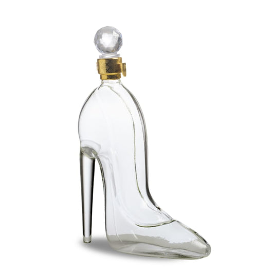 Clear glass shoe-shaped bottle with a gold cap on a white background