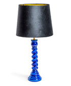 A table lamp with a tapered black fabric shade featuring a gold inner lining, supported by a glossy cobalt blue spiral base on a white background.
