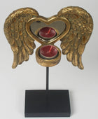 Decorative candle holder with gold angel wings and a heart design on a white background