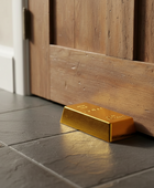 Gold bar on a tiled floor next to wooden paneling