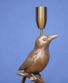 Bronze bird-shaped candle holder against a blue background