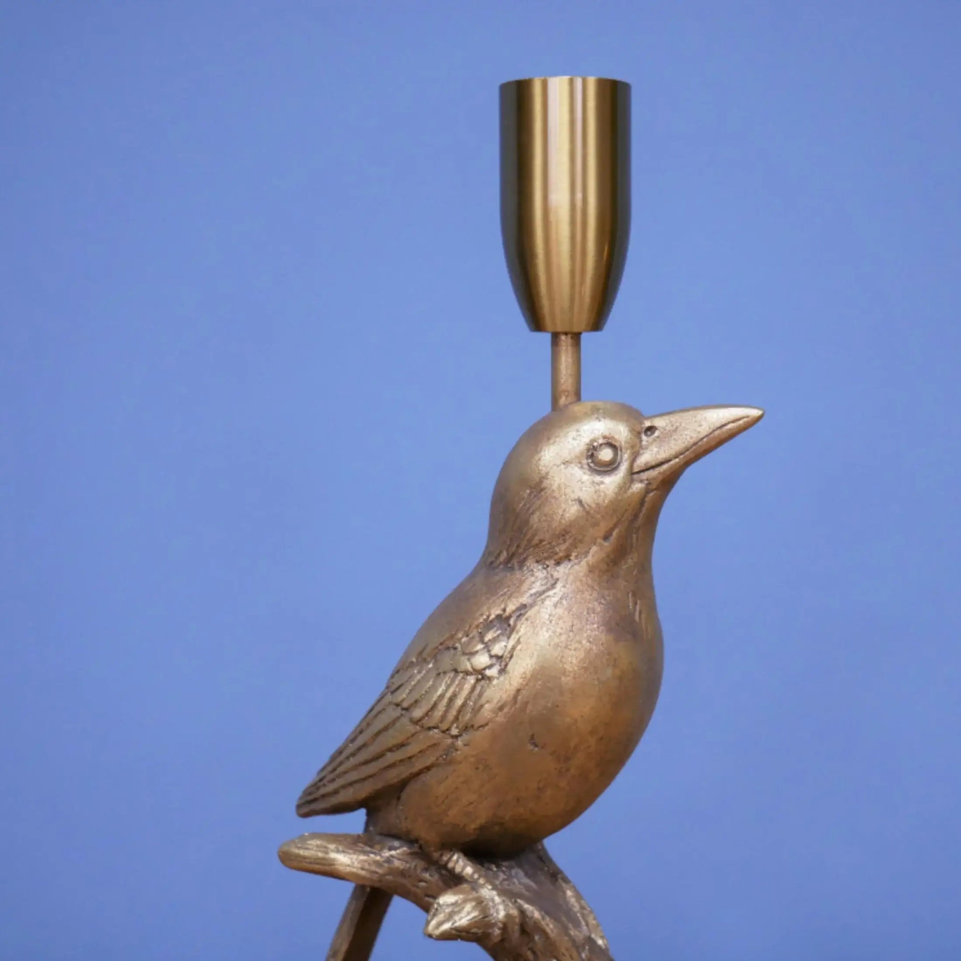 Bronze bird-shaped candle holder against a blue background