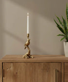 Decorative candle holder with bird design on a wooden surface with books and a plant.