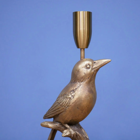 Bronze bird-shaped candle holder against a blue background