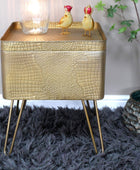 Gold textured side table with decorative items on a dark rug