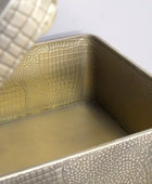 Metallic textured container with a lid on a light gray background