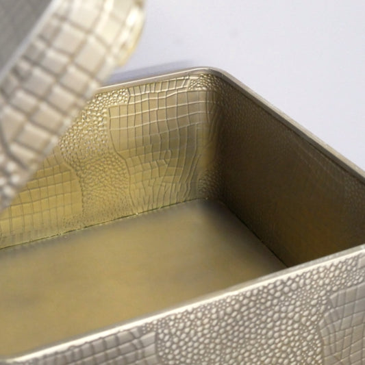 Metallic textured container with a lid on a light gray background