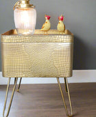Gold textured side table with a lamp and decorative birds on a gray wall background