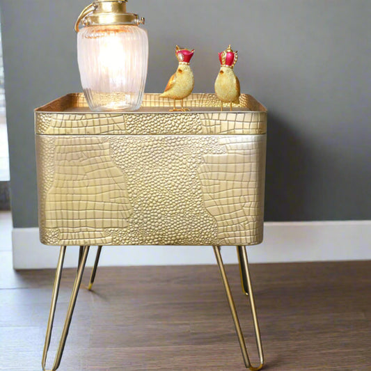Gold textured side table with a lamp and decorative birds on a gray wall background