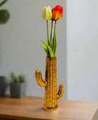 Gold cactus-shaped vase with tulips on a wooden surface
