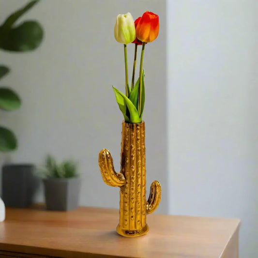 Gold cactus-shaped vase with tulips on a wooden surface