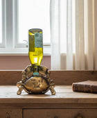 Decorative bottle holder with a bottle on a wooden surface near a window.